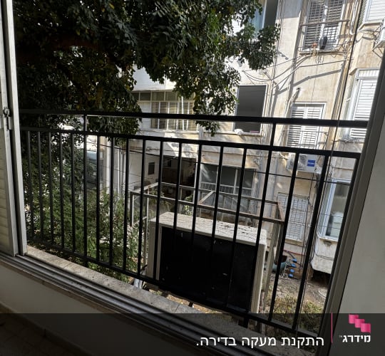 מעקה ברזל במרפסת עם נוף לבניינים ועצים